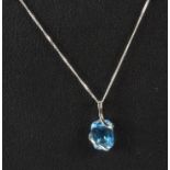 A 9ct white gold blue topaz set pendant and chain.