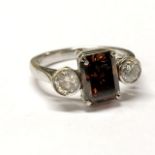 An 18ct white gold ring set with an emerald cut fancy intense brown diamond and brilliant cut