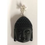 A carved obsidian and crystal Buddha head pendant. H.6.5cms