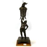 A 19th Century Japanese bronze figure of a sumo wrestler holding a dragon vase and cover above his