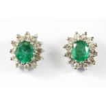 A pair of yellow and white metal (tested 9ct gold) emerald and diamond set cluster earrings.