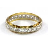 An 18ct yellow and white gold stone set full eternity ring, (P).