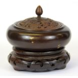 A Chinese cast bronze censer with gilt splash decoration on a carved wooden base, Dia. 11cm