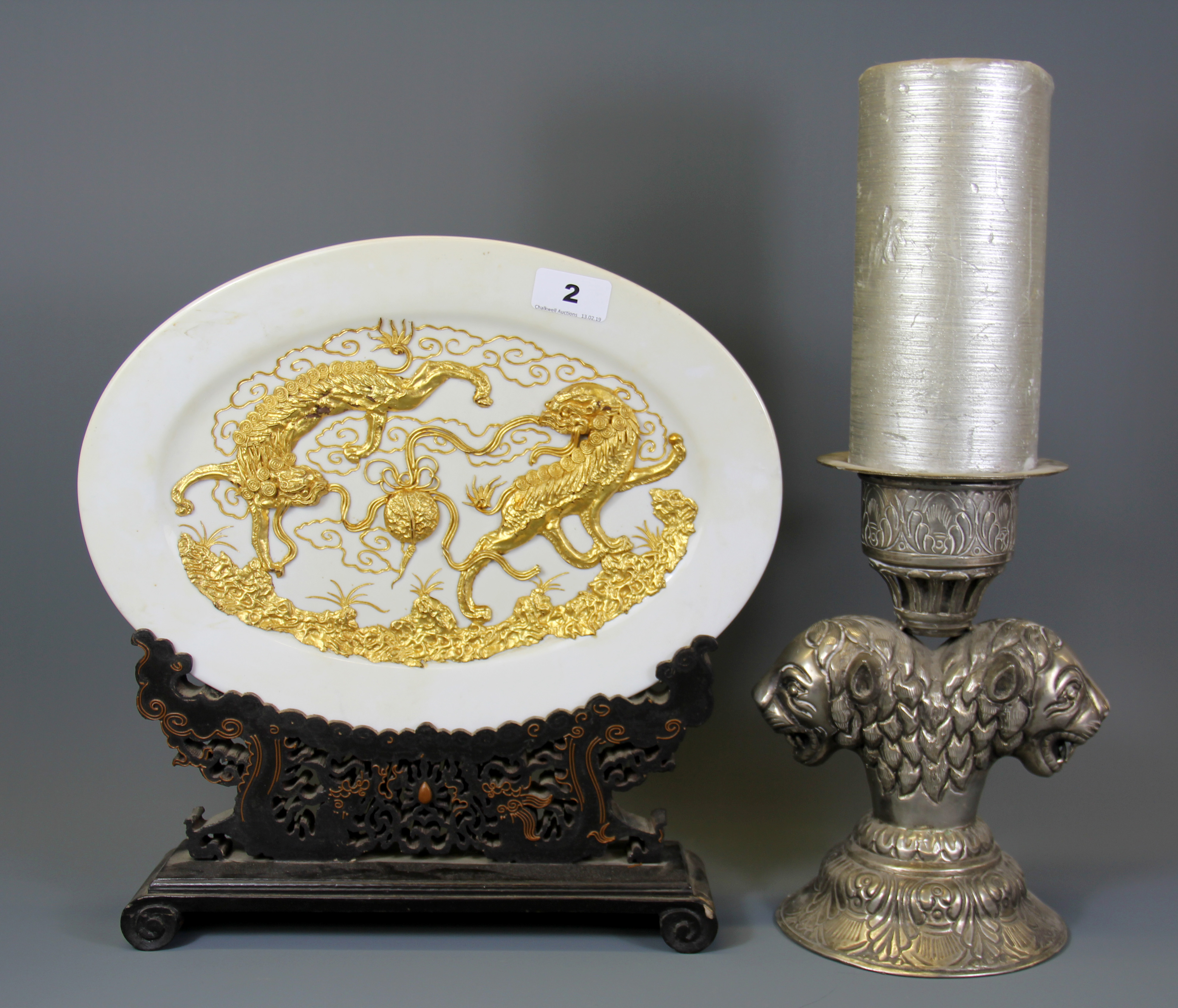 An oriental gilt decorated plate on a carved wooden stand together with a white metal lion head