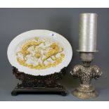 An oriental gilt decorated plate on a carved wooden stand together with a white metal lion head