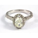 An 18ct white gold (stamped 750) halo ring, set with an oval cut diamond and diamond set