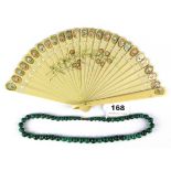 A strand of polished malachite beads and a 1920's celluloid fan.