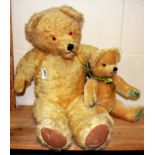 A large articulated straw filled teddy bear, H. 56cm together with a further teddy bear.