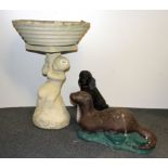 An old concrete bird bath with a poodle and an otter.