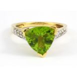 A large 18ct yellow gold ring set with a trillion cut peridot and diamond set shoulders, peridot