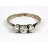 A white metal (tested platinum) three brilliant cut diamond set ring, (L.5).