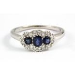 An 18ct white gold cluster ring set with three oval cut sapphires and diamonds, (K.5).