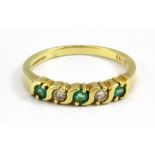 An 18ct yellow gold emerald and diamond set half eternity ring, (N.5).