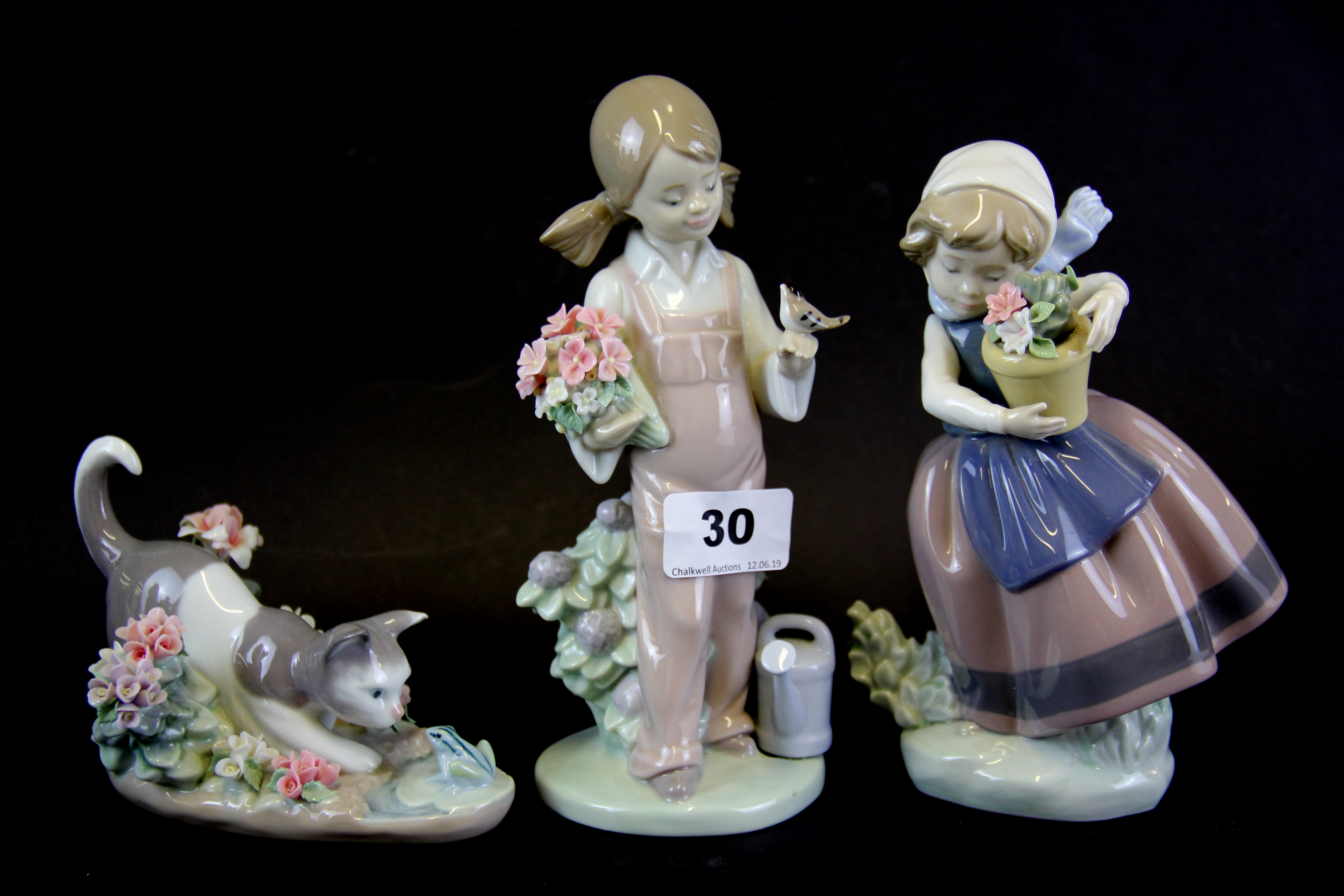 Three Lladro porcelain figures of girls and a cat, tallest H. 18cm.