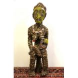 A large Oceanic carved wood and cowrie shell and bead decorated figure of a woman nursing a baby, H.