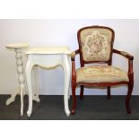 An upholstered armchair with a painted side table and plant stand.