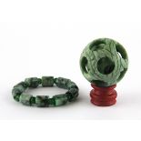 A Chinese carved green jade and green cornelian bracelet and carved ball in ball.