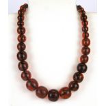 A graduated necklace of reconstituted amber beads, largest Dia. 22mm.