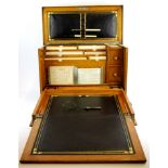 A 1900 fitted light oak writing slope and stationery box still with original calendar and envelopes,