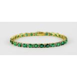 An 18ct yellow gold (stamped 750) bracelet set with oval cut emeralds and diamonds.