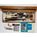 A wooden box containing vintage gentleman's watches, lighters, pocket knives and other small items.