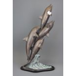 A bronze sculpture of dolphins jumping over waves, H. 57cm.