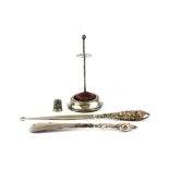Four hallmarked silver items; a thimble, a hat pin stand and a silver handled lace hook and