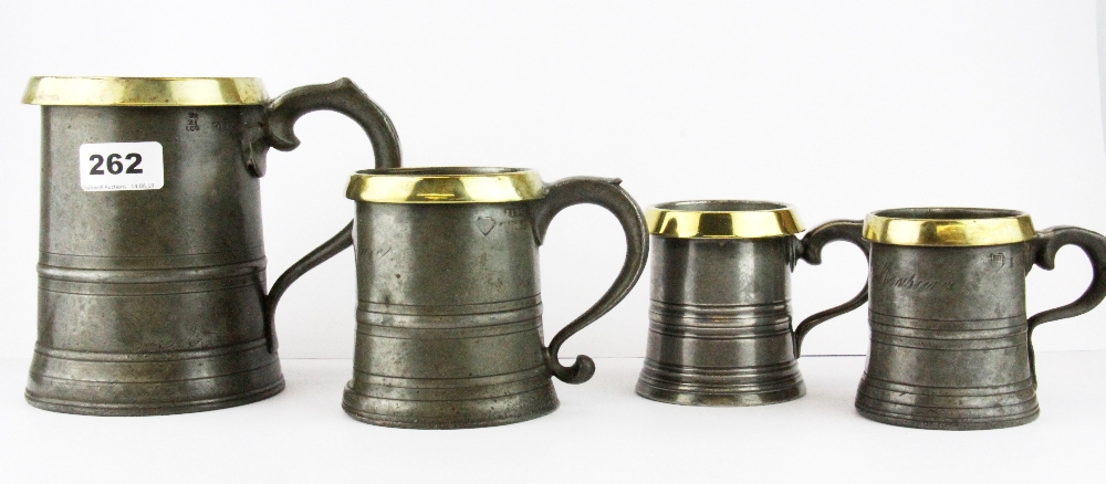 A set of four pewter and brass rimmed graduated tankards, tallest H. 15.5cm.