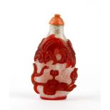 A two layer Peking glass snuff bottle with a carved coral stopper, H. 8cm.