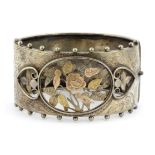 A hallmarked silver bangle with yellow and rose gold ornament, L. 6.5cm.