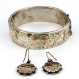 A hallmarked silver bangle with yellow and rose gold ornament, together with a similar pair of