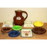 A stoneware carriage brewery advertising jug and a quantity of advertising ashtrays.