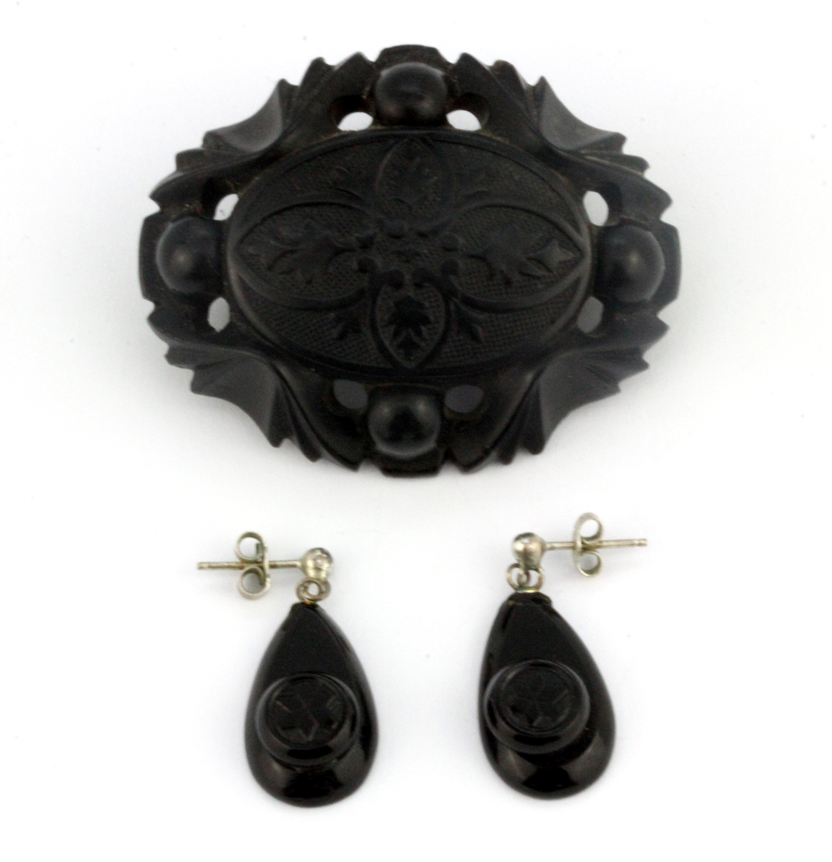 A carved jet brooch together with a pair of jet earrings, L. 5cm.