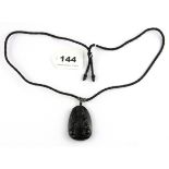 A fine carved obsidian amulet of the Buddha on a silk cord, L. 5cm.