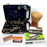 A cased clarinet with a harmonica, stylophone, tambourine and small drum.