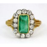 A yellow metal (tested 18ct gold) ring set with a scissor cut Columbian emerald surrounded by