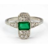 An Art Deco platinum ring set with a baguette cut emerald and brilliant cut diamonds, (P).
