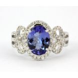 An 18ct white gold (stamped 750) ring set with an oval cut tanzanite and diamonds, (O).