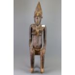 A tall African Punu tribal carved wooden figure of a woman sitting on a stool, H. 78cm.