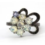 A 925 flower shaped ring set with black spinel and round cut opals and tanzanite, (O).