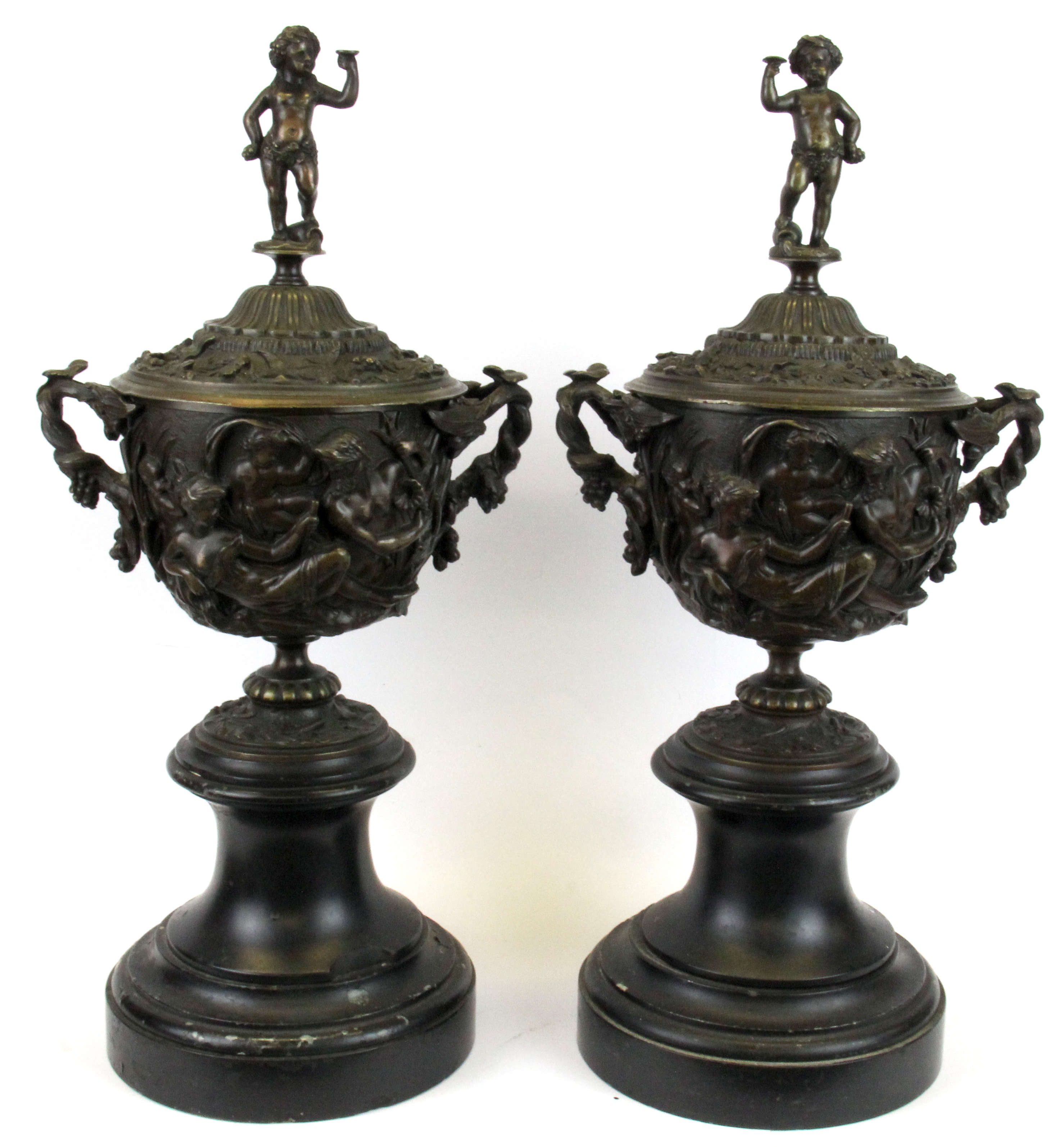 A pair of 19th Century bronze urns and lids on marble bases with Bacchanalian decoration, H. 41cm.