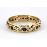 A 9ct yellow gold (stamped 9ct) full eternity ring set with garnets and white stones, (P.5).