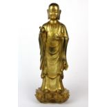 A Tibetan gilt bronze figure of the standing Buddha with his feet on two separate lotus, H. 38cm.