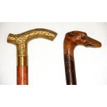 An interesting carved greyhound head walking stick and a modern brass handled walking stick