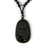 A lovely Chinese carved obsidian amulet of the Goddess Guanyin, H. 5.5cm on an obsidian bead