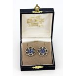 A boxed pair of 9ct white gold flower shaped stud earrings set with round cut sapphires, Dia. 2cm.
