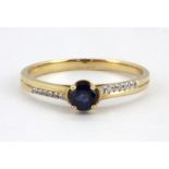 A 14ct yellow gold (stamped 585) sapphire set solitaire ring with diamond set shoulders, (Q).