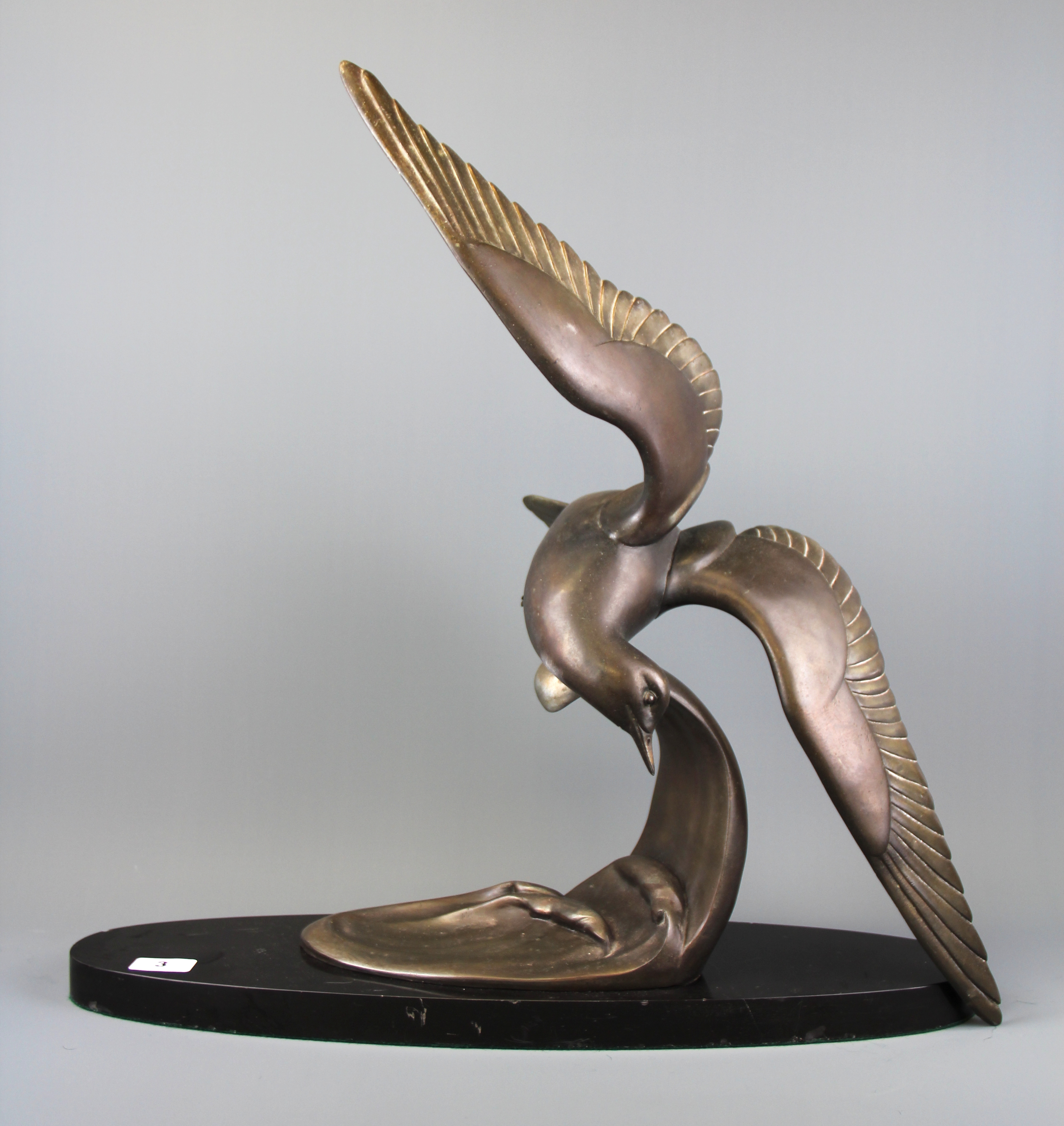 An original bronzed spelter sculpture of a seagull flying over waves on a marble plinth, H. 57cm, L.