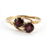 A 9ct yellow gold garnet set crossover ring, (O).