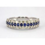 An 18ct white gold (stamped 750) half eternity ring set with a row of round cut sapphires flanked by